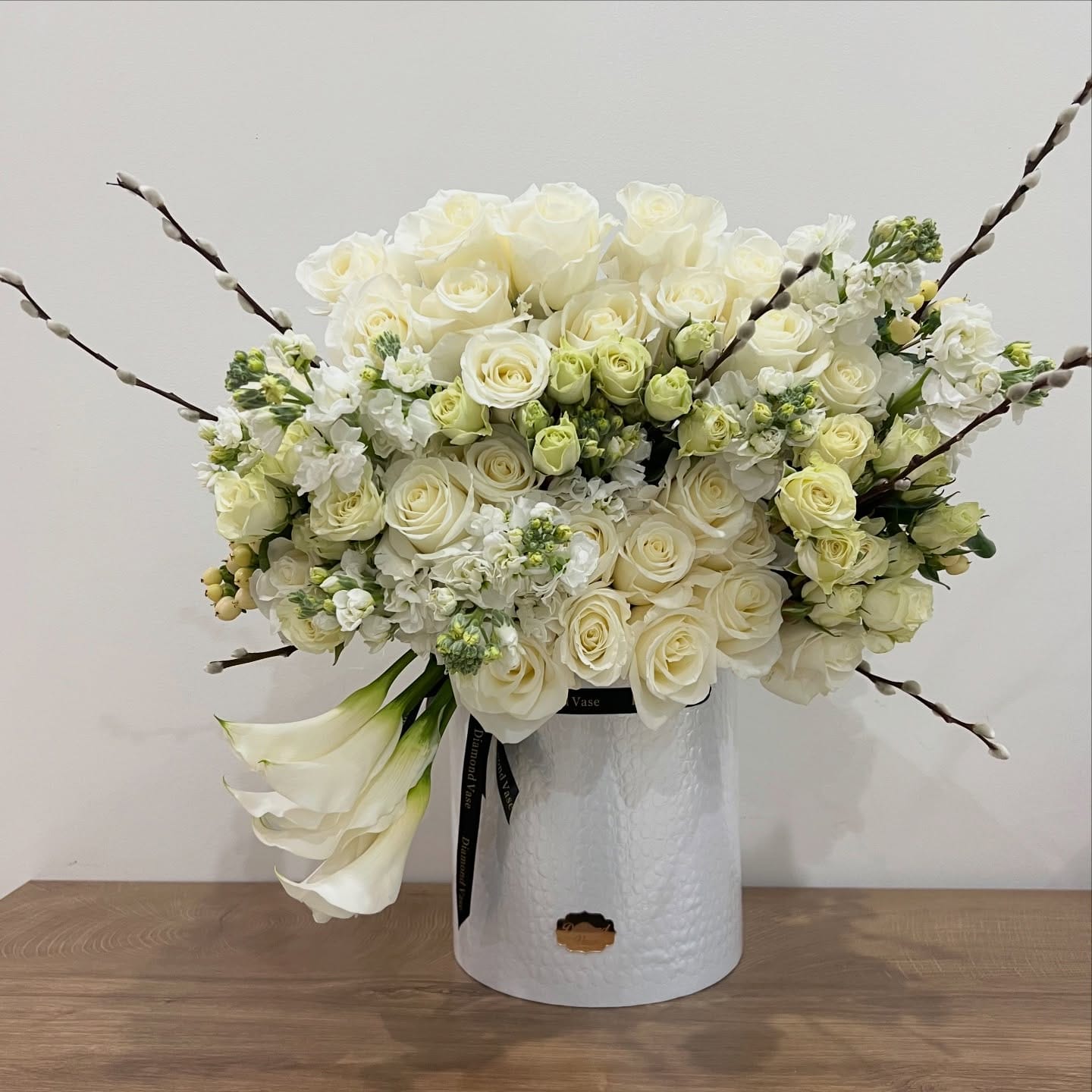 All-white roses, stock and calla lilies with pussy willow in a white textured Diamond Vase box