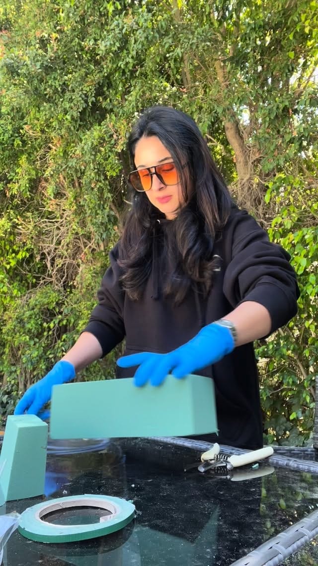 Bita in blue gloves preparing floral foam blocks at an outdoor event setup