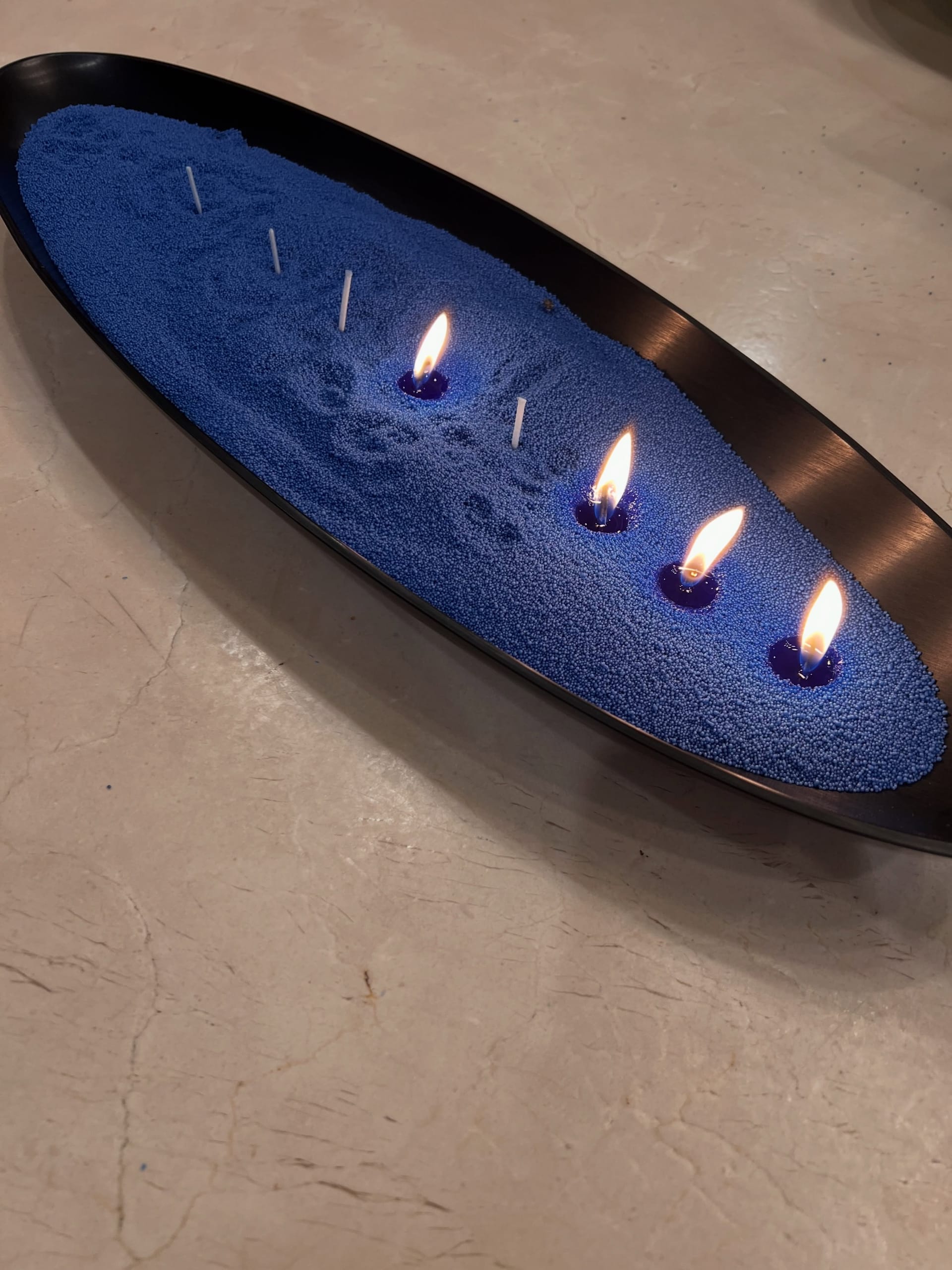 Royal-blue sand candle tray with four lit wicks, from the Diamond Vase rental collection